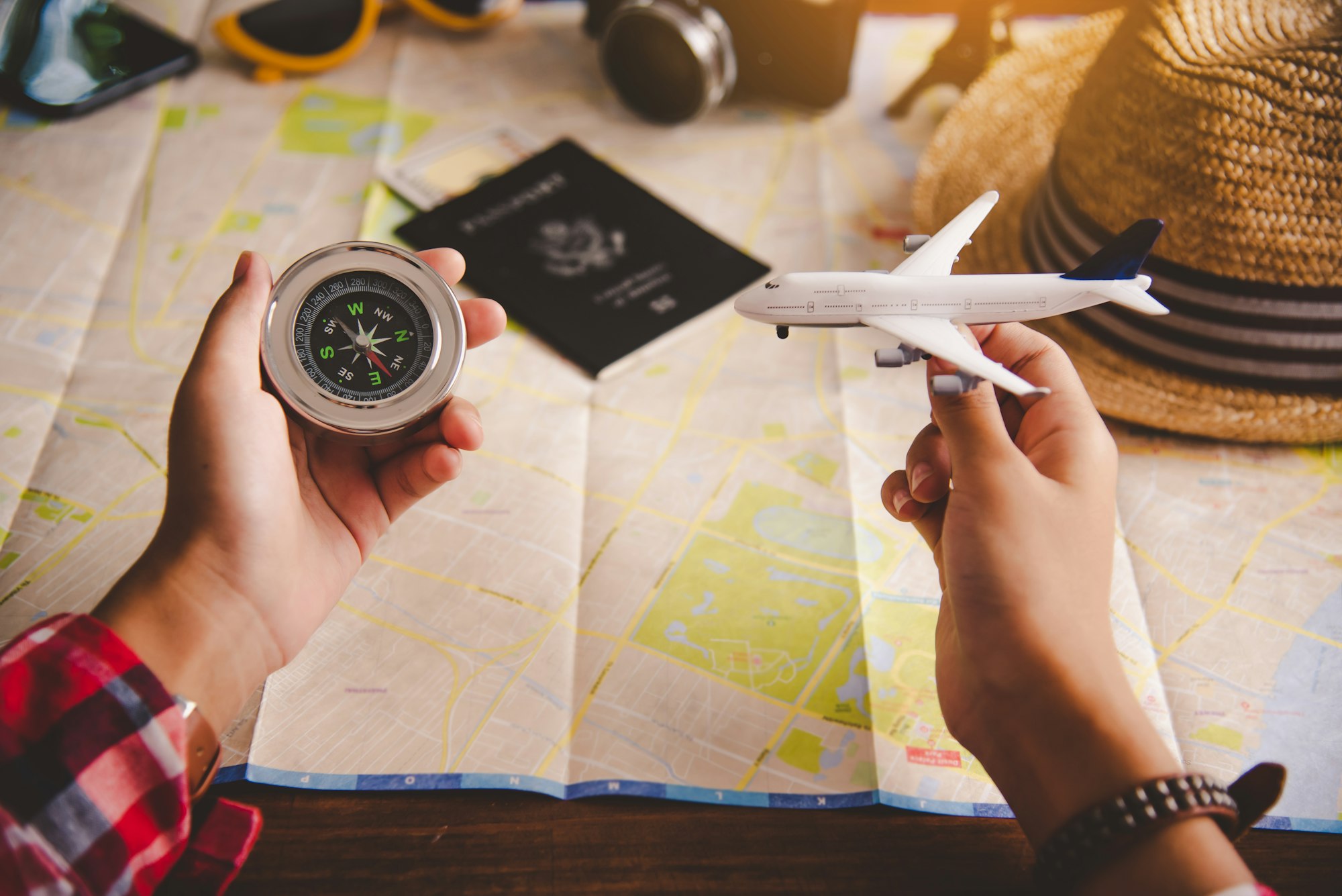 Tourists hold a compass and locate a place on a world map.